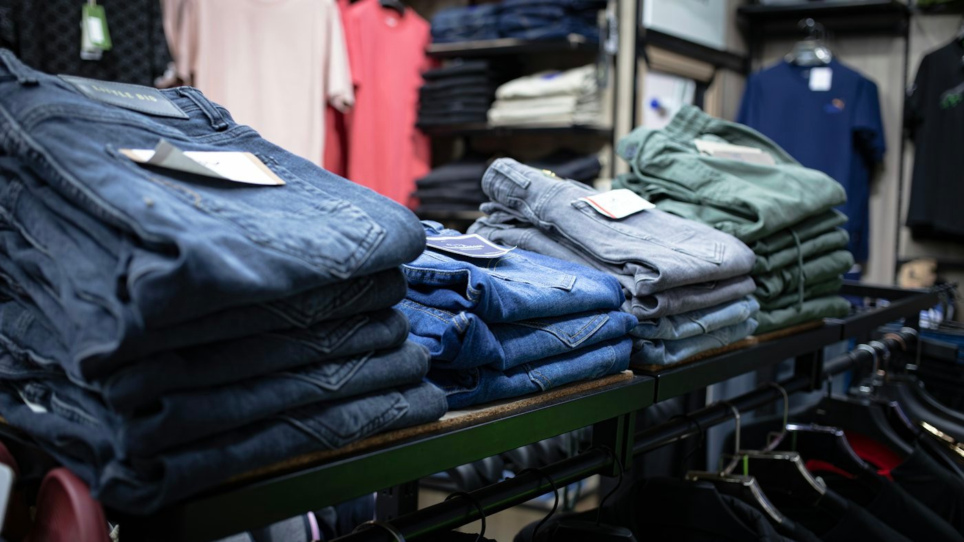 Stacks of folded jeans in several washes and sizes on a shelf