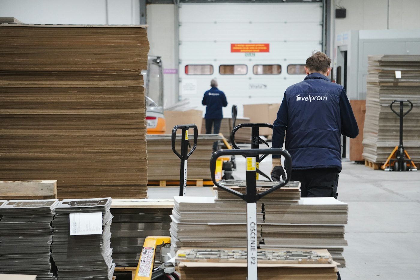 A warehouse worker moving a cart of cartons across a fulfillment floor